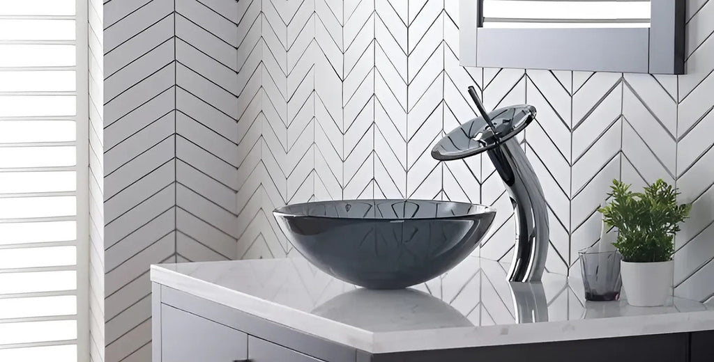 Diseño de baños con uso de piedra natural y grifo de acero inoxidable tipo cascada con disco de cristal.