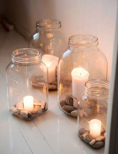 velas encendidas dentro de jarrones de cristal con piedras