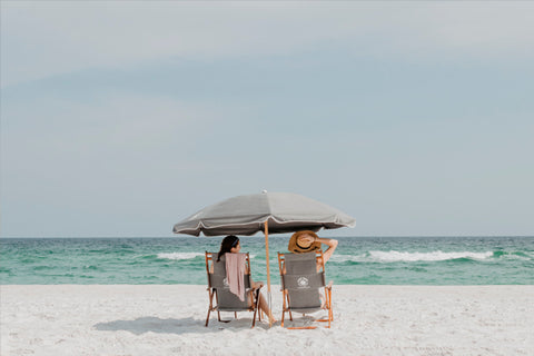 dos chicas sentadas en hamacas en la playa con sombrilla