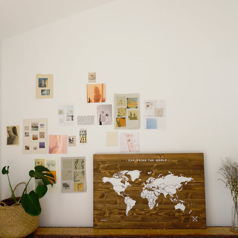 mapa de madera colocado junto a fotos polaroid pegadas a la pared