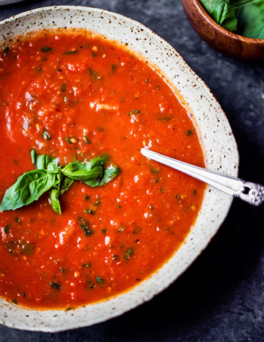 Roasted Heirloom Tomato Soup in a bowl with basil and a spoon
