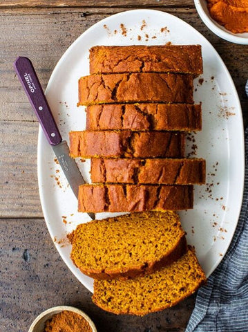Pumpkin bread sliced on a speckled white place on a wooden table