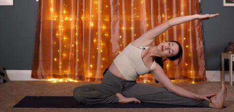 woman doing a side yoga stretch with an orange lighted background