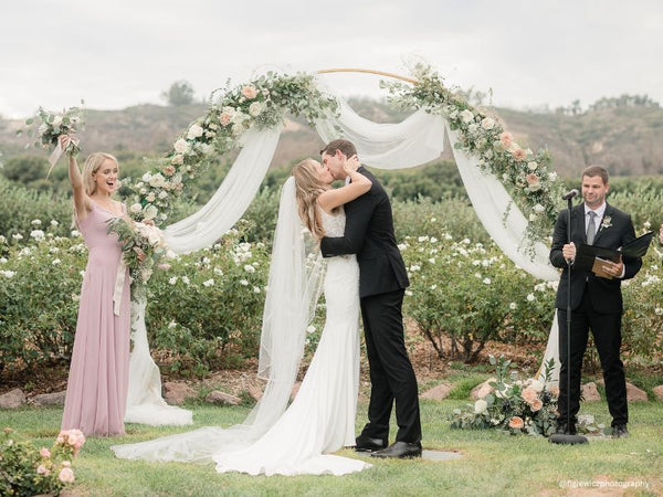 Bride and Groom Kissing Under the Floral Wedding Arch