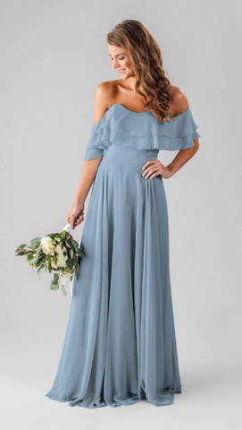 Kennedy Blue model wearing a whimsical gown with a sweetheart neckline and a ruffled top with off the shoulder straps.