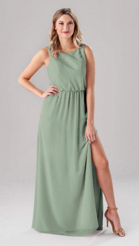 Kennedy Blue model wearing an elegant dress with a high scooped neckline and a side slit. 