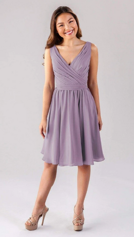 Kennedy Blue model wearing a lovely knee-length dress with a ruched bodice and flowy skirt. 