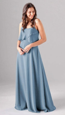 Kennedy Blue model wearing a lovely dress with an asymmetrical ruffled blouse and scooped neckline with a flowy skirt.