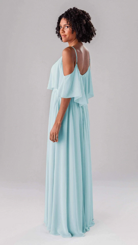 Kennedy Blue model wearing a whimsical gown with a ruffled bodice and a flowy skirt. 