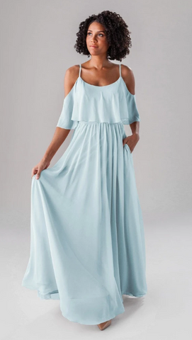 Kennedy Blue model wearing a whimsical gown with a ruffled bodice and a flowy skirt. 