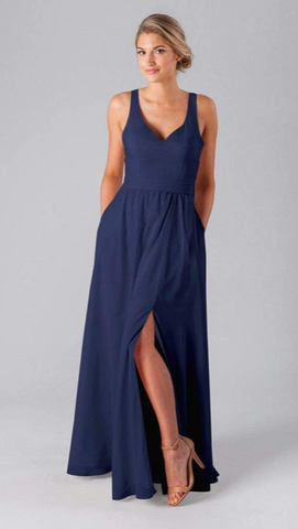 Kennedy Blue model wearing an elegant dress with a low v-neckline and an A-line skirt with a side slit.
