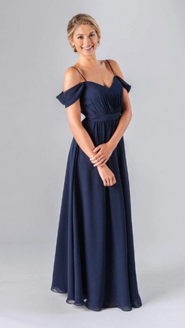 Kennedy Blue model is wearing an elegant gown with a sweetheart neckline, off the shoulder straps, a ruched bodice, and a flowy skirt.