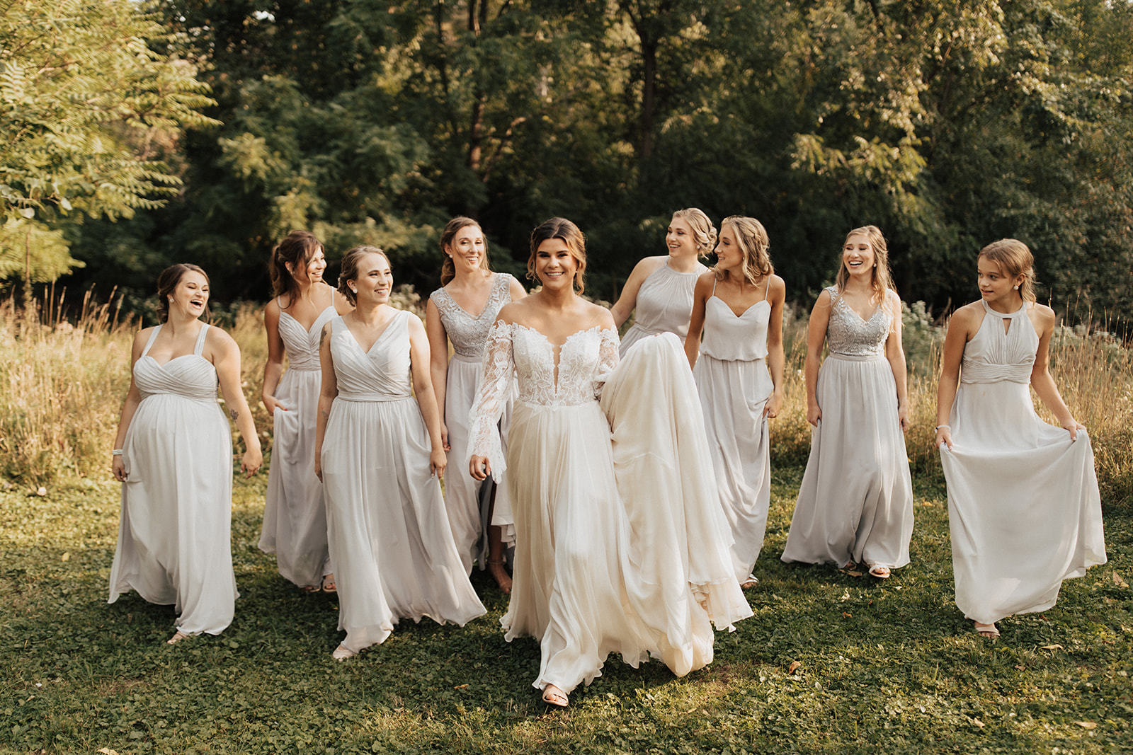 Bride and Bridesmaids wearing Kennedy Blue Bridesmaid Dresses in 'Dew Drop' walking through a field.