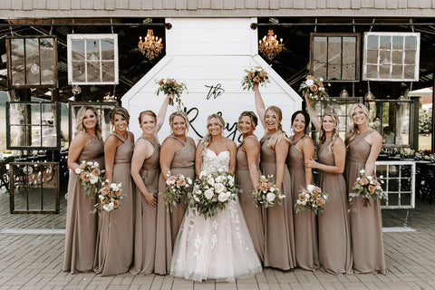 Bride and Bridesmaids gathered together and smiling.