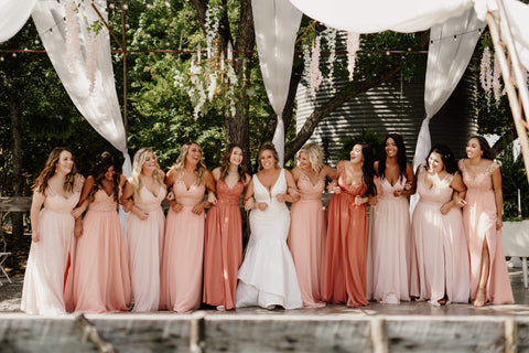 Bride and Bridesmaids smiling and walking with arms linked together.
