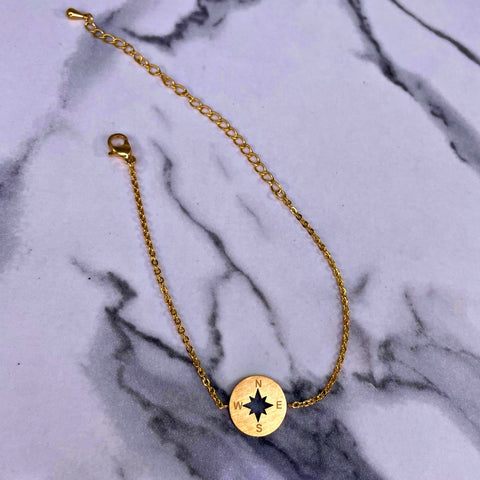 dainty compass bracelet on a marble table backdrop sold by OurCoordinates