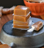 A stack caramel candy that is being placed in individual wrappers.