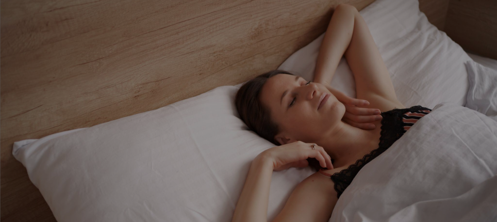 A lady in bed and looking happing because she slept well.