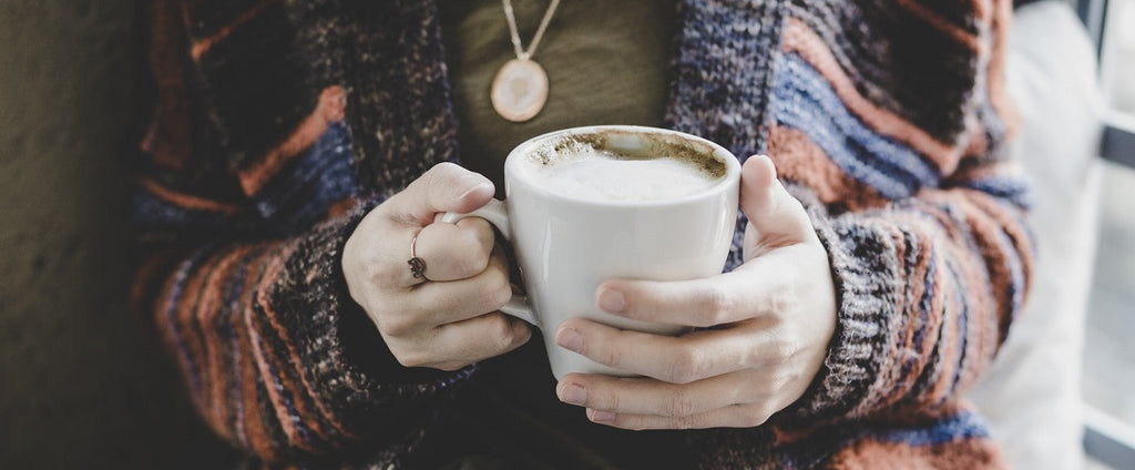 Person holding a hot AVB coffee with milk.