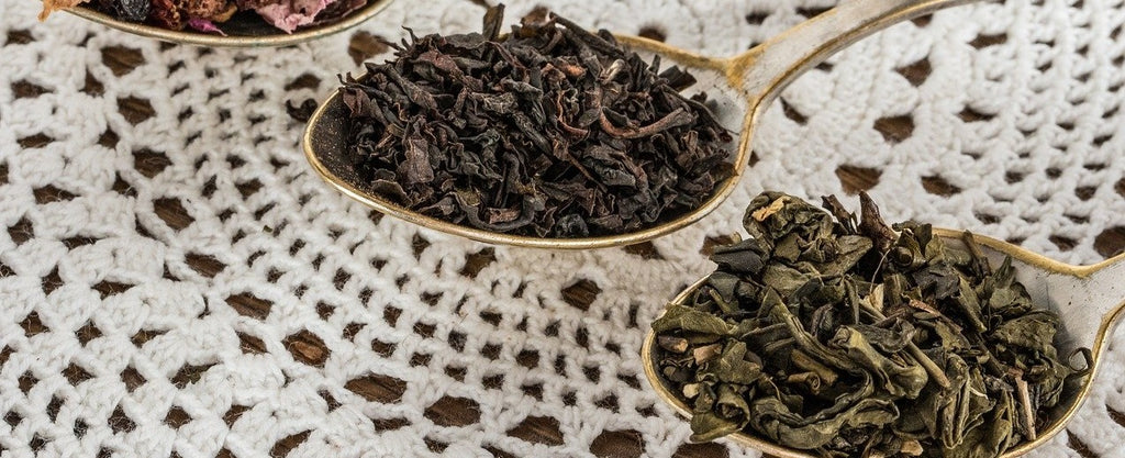 Spoons filled with loose leaf black tea and green tea.