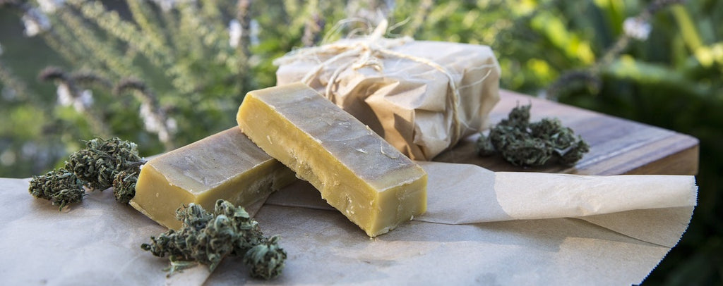 Sticks of cannabutter on table outdoors with some fresh marijuana beside it.