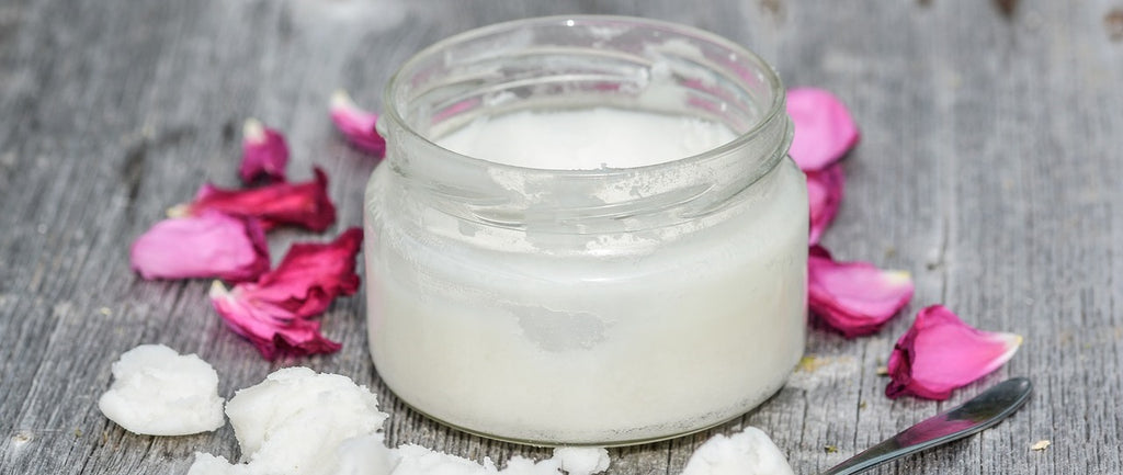 A jar of coconut oil surrounded by flowers.