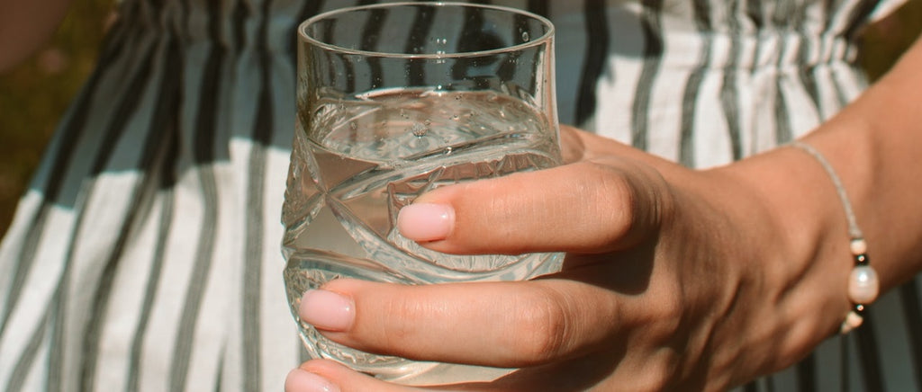 A glass of water being held by a hand.