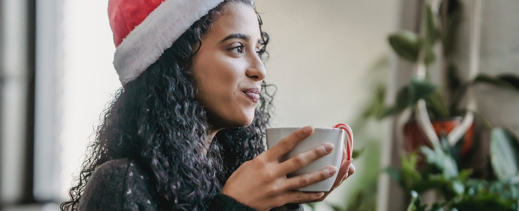 A person smiling while drinking a cup of hot cocoa.