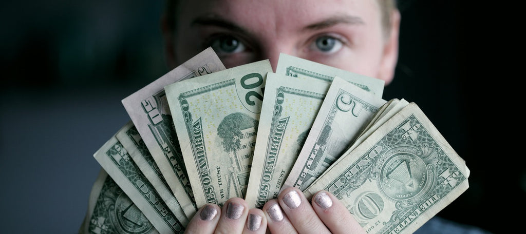 A person holding a wad of money in front of their face.