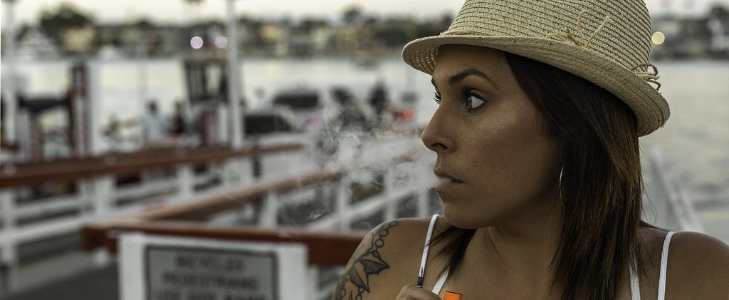 A person vaping dry herb on a dock with a portable vaporizer.