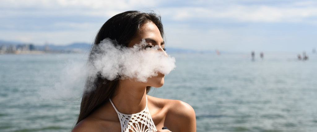 A person vaping butane hash oil (BHO) outside near water.