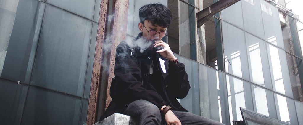 Person sitting outside and vaping using a portable vaporizer.