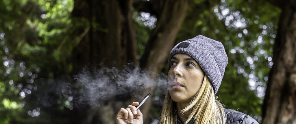 A person vaping cannabis in a forest.