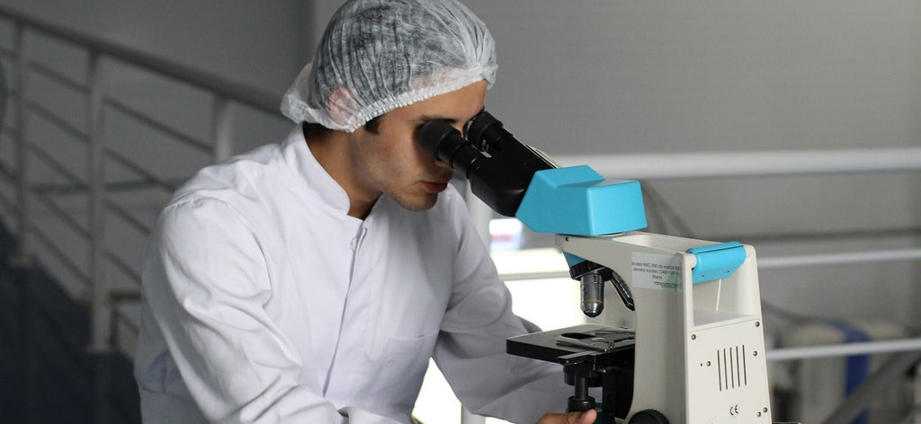 A scientist wearing a lab coat using a microscope.