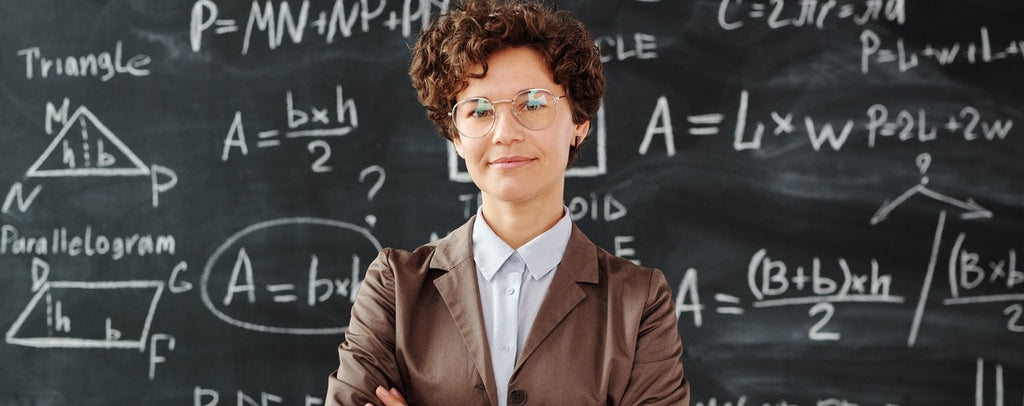 A researcher standing in front of a blackboard with equations written on it.