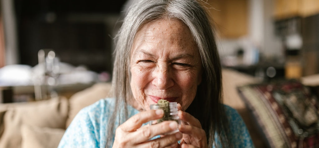 A person smiling and holding a jar of cannabis flower.