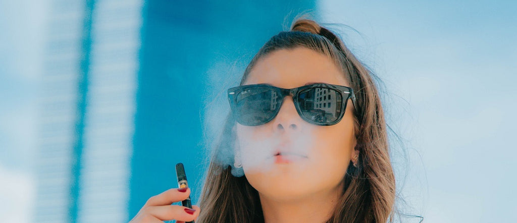 Person wearing sunglasses and vaping hash in a portable vaporizer.