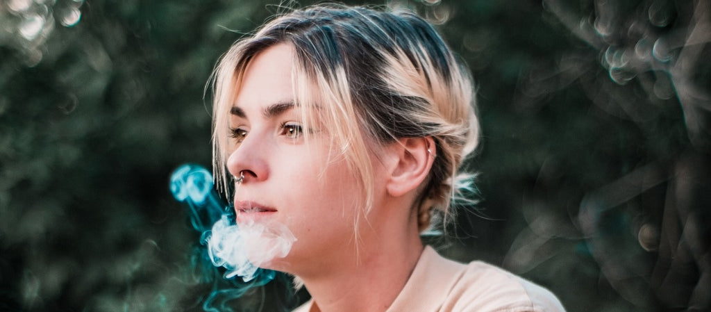 A person using a portable dry herb vape outside.