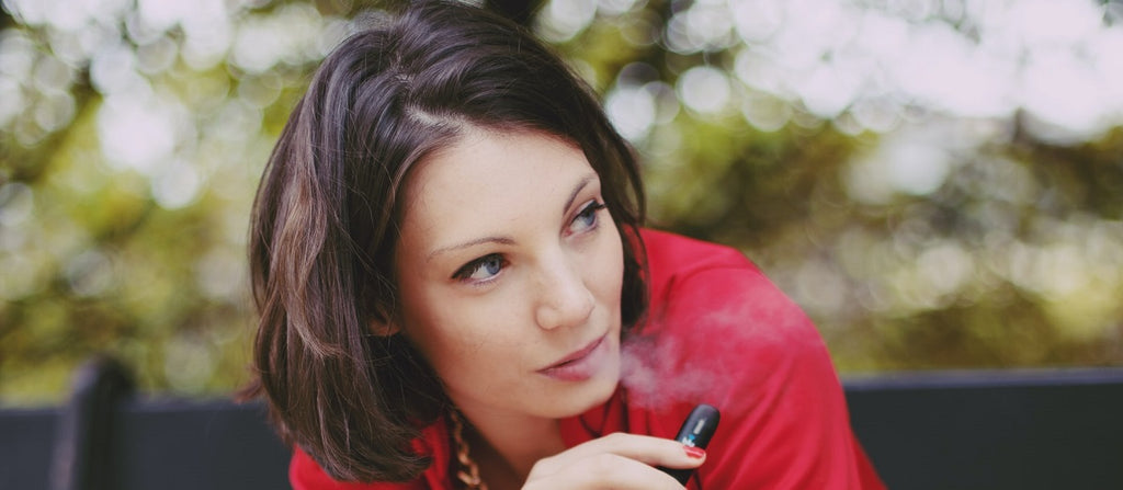 Person outside exhaling vapor from a portable dry herb vaporizer.