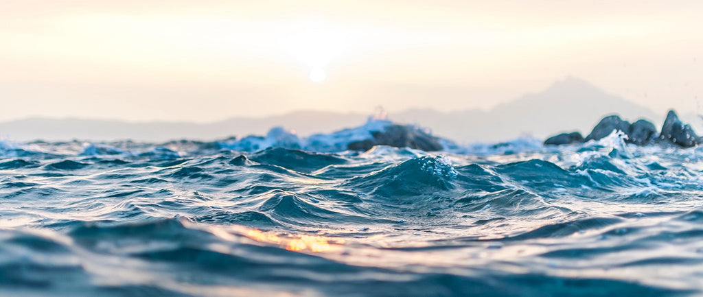 Waves on the water, with mountains in the far background.