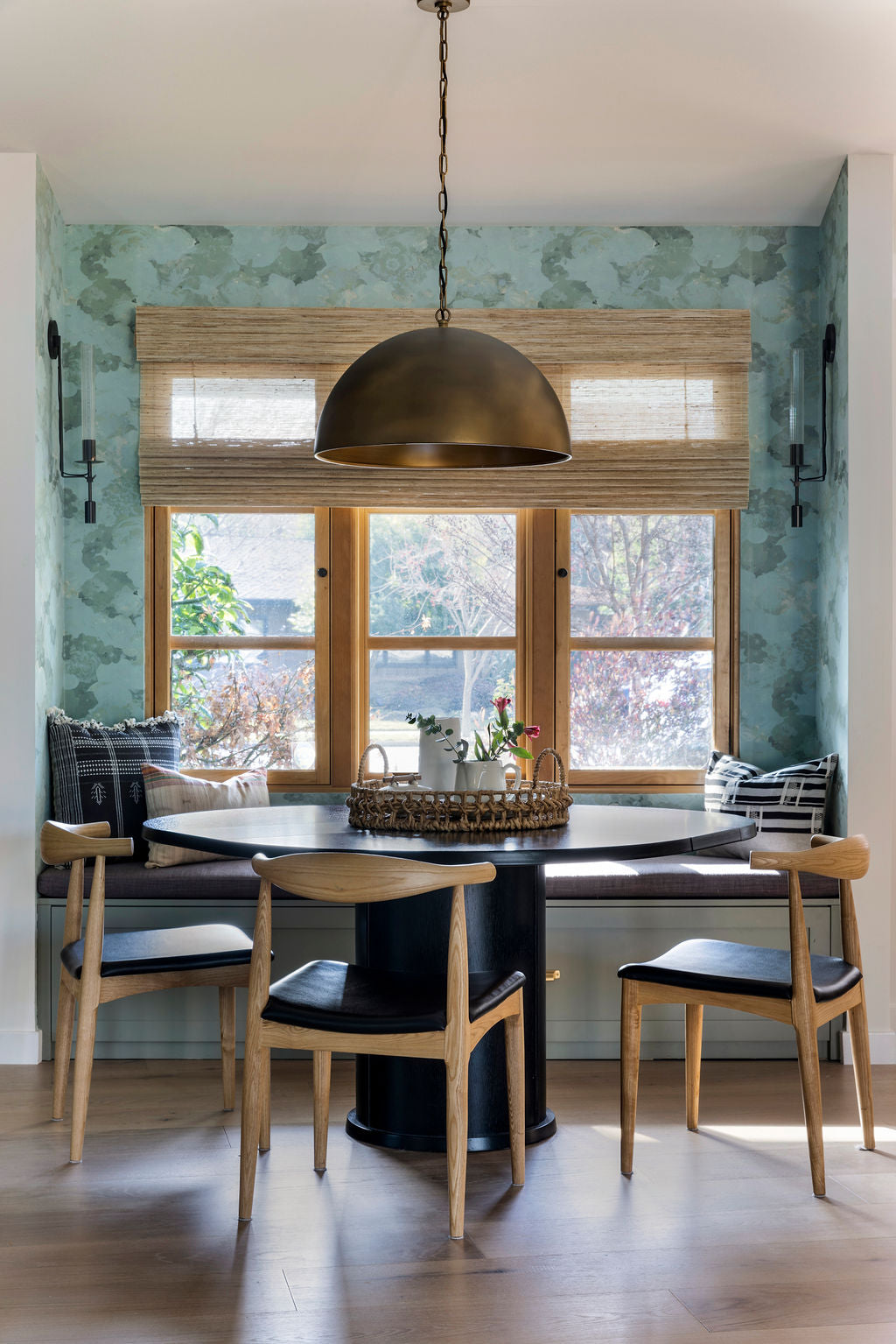 Detail photo of a kitchen table in front of a window decorated with green and bronze elements.