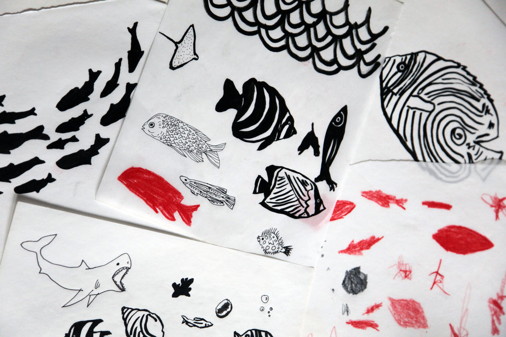 Illustrations of fish on multiple pieces of paper, drawn in black and red