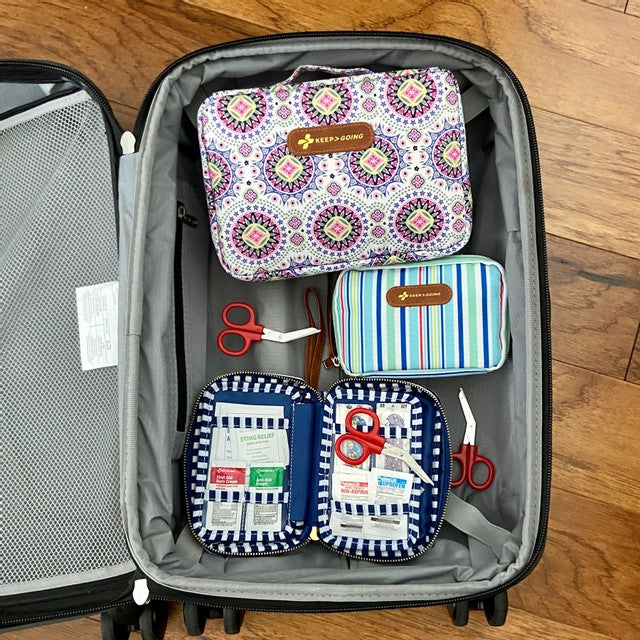 Open suitcase displaying organized travel accessories including patterned bags and a pair of scissors.