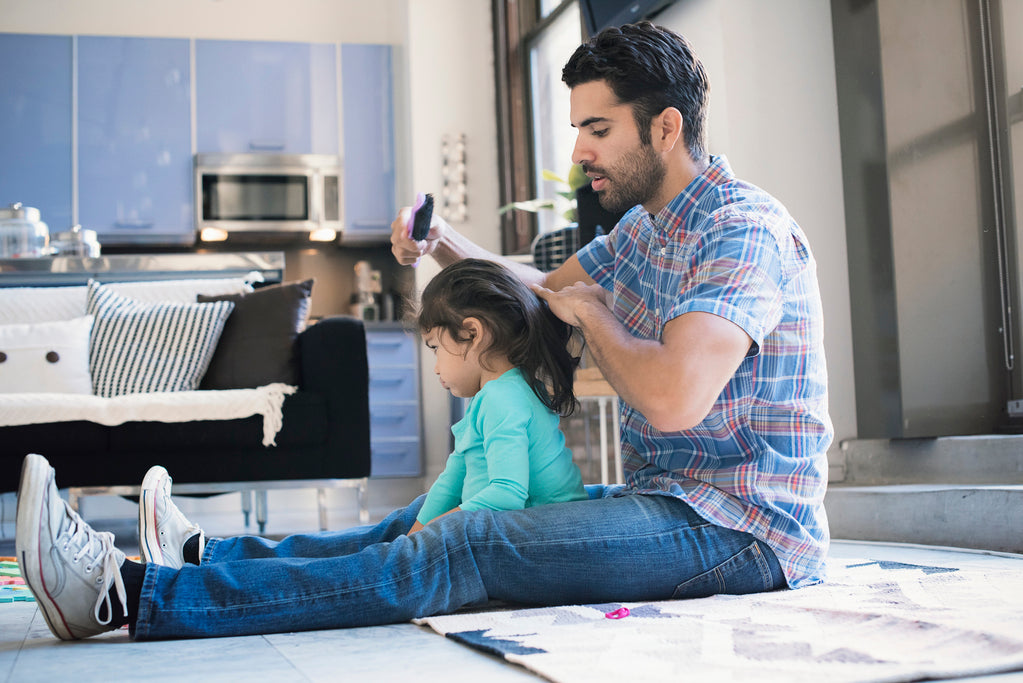 Foto de papá peinando a su hija en el suelo paternidad responsable y activa