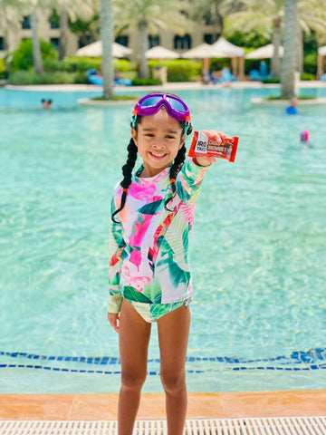 proyouth choco brownie nutritional performance bar held by child, girl next to swimming pool