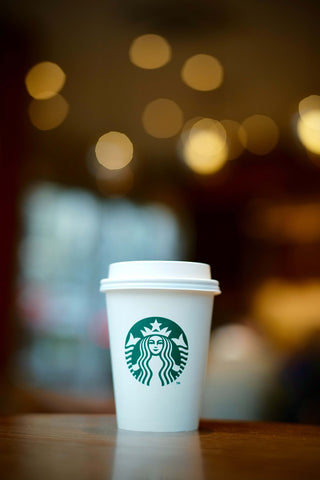 A white Starbucks cup in front of blurred lights