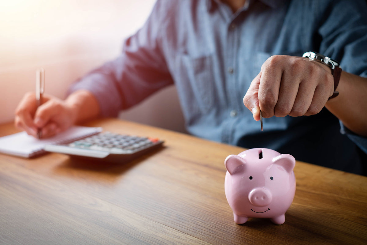 Person budgeting the cost of new technology putting coin in piggy bank