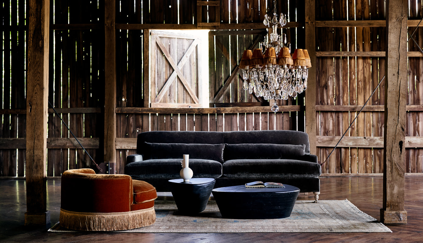 Orange Velvet chair, grey velvet sofa, chandelier and other home decor in a barn