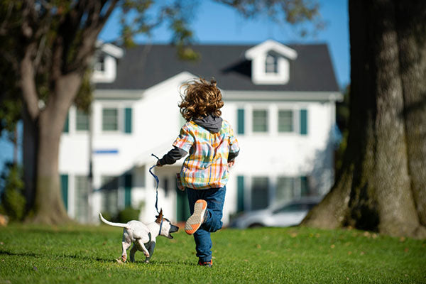 kid running with dog on leash
