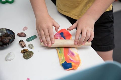 Child's hand rolling playdough next to an assortment of crystals